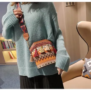 Dettaglio della borsa a secchiello intrecciata boho con nappe colorate e motivi etnici