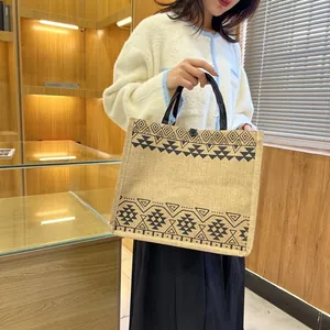 Detail of linen tote bag with ethnic geometric pattern, black handle and single button closure