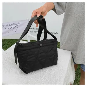 Detail of black quilted shoulder bag featuring stitched rhombus pattern and wide strap
