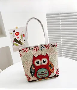 Dettaglio del ricamo a civetta su borsa vintage in tela con motivi floreali