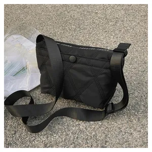 Detail of black quilted crossbody bag with adjustable wide strap and snap button closure