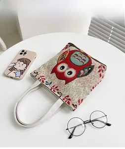 Dettaglio di borsa vintage in lino con ricamo a forma di gufo colorato su tessuto