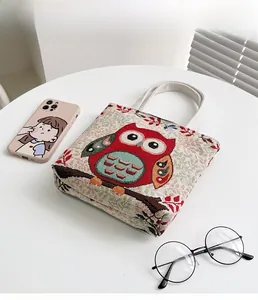 Dettaglio del gufo ricamato su una piccola borsa a mano in cotone e lino beige da donna