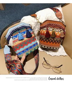 Dettaglio di borse a secchiello boho con motivi geometrici in maglia e nappe decorative