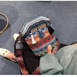 Dettaglio dei ricami etnici e delle nappe con frange sulla borsa a secchiello tessuta