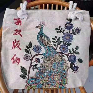 Detailed embroidery of peacock and flowers on ivory canvas tote bag with rope handles