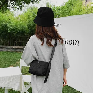 Outdoor shot of a black quilted crossbody dumpling bag worn by a model in casual wear
