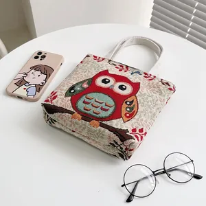 Borsa a mano retrò con gufo ricamato su tavolo bianco con telefono e occhiali