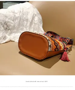 Dettaglio borsa a secchiello boho con ricami etnici e nappe colorate