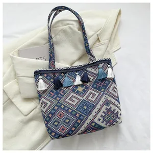 Close-up of ethnic woven tote bag featuring geometric patterns and colorful tassel charms