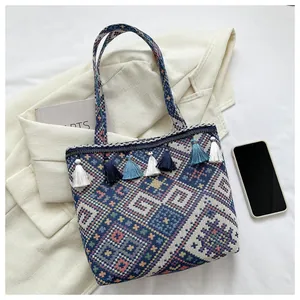 Detail of bohemian woven tote bag featuring colorful geometric patterns and blue tassels