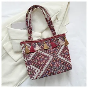 Detailed close-up of ethnic woven tote bag with colorful tassels on a white blazer