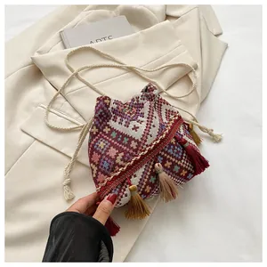Detail of bohemian bucket bag with geometric patterns, long tassels and woven strap