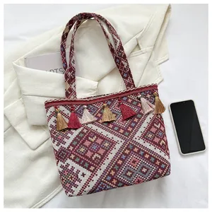 Detail of bohemian woven tote bag featuring geometric patterns and colorful tassels