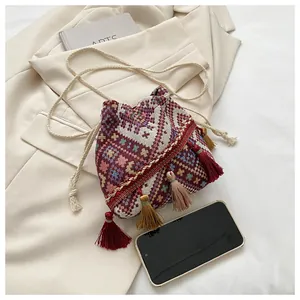 Detailed macro view of woven boho bucket bag with colorful tassels and soft drawstring strap