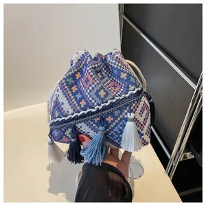 Detail of blue geometric woven bucket bag with colorful tassels and white drawstring