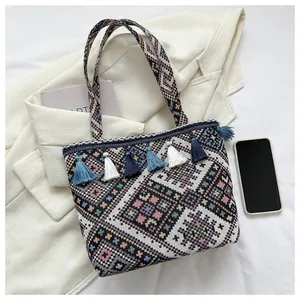 Detail of woven ethnic tote bag with colorful geometric patterns and blue tassel accents