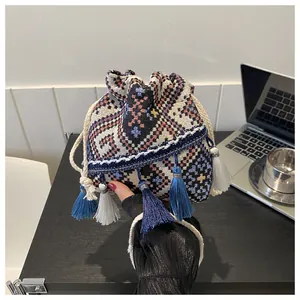Detailed shot of ethnic bucket bag featuring geometric weave and blue fringe tassels