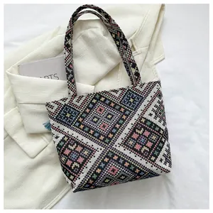 Close-up of geometric knit pattern and blue tassel detail on a large tote bag