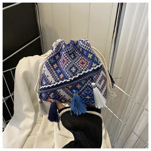 Close-up of geometric woven bucket bag with blue and white tassels and cotton drawstring