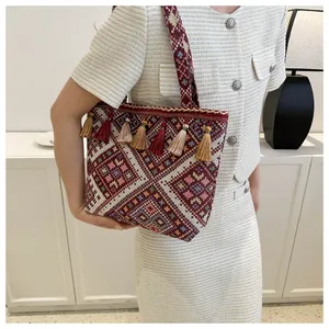 Detailed view of bohemian woven tote bag featuring ethnic geometric patterns and colorful tassels