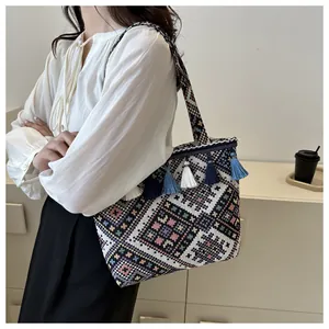 Detail view of ethnic bohemian woven tote bag featuring floral patterns and tassels
