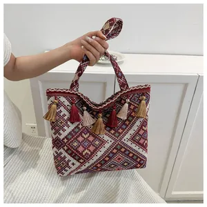 Close-up of ethnic woven tote bag with bohemian geometric patterns and colorful tassels