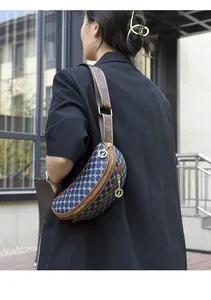Dettaglio della borsa a tracolla in tela jacquard blu scuro indossata da una modella in nero