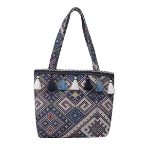 Detailed close-up of woven geometric jacquard pattern and colorful fringe tassels on a tote