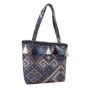 Detail of bohemian woven tote bag showing geometric patterns and vibrant blue tassels
