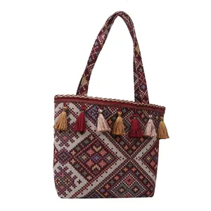 Macro detail of geometric jacquard fabric and colorful tassels on an ethnic tote bag