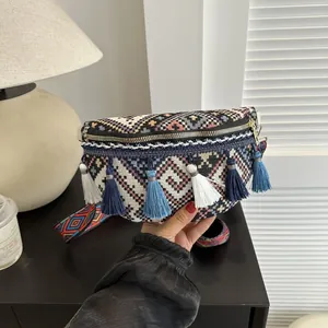 Détail d'un sac banane ethnique tissé avec motifs géométriques et pompons bleus