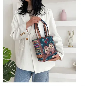 Detailed view of bohemian style woven handle and owl embroidery on blue fabric tote bag