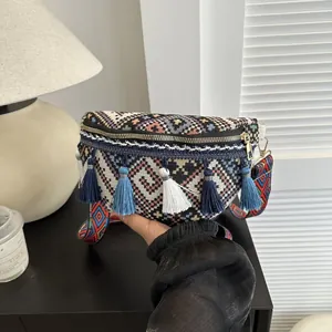 Détail d'un sac bohème tissé avec motifs géométriques colorés et pompons à franges
