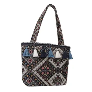 Macro view of ethnic jacquard tote bag featuring geometric rhombus patterns and blue tassels