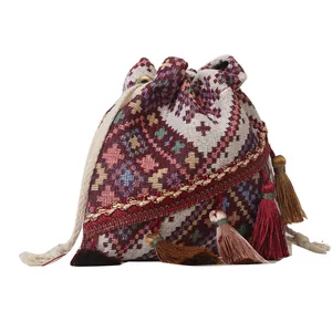 Bolso saco étnico con patrones geométricos y borlas de colores al estilo bandolera
