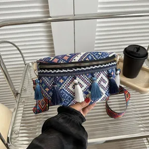 Détail de la sacoche bohème avec pompons bleus et bandoulière tissée aux motifs colorés