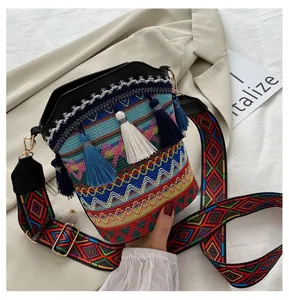 Borsa a secchiello boho con motivi etnici intrecciati, nappe e tracolla larga stampata
