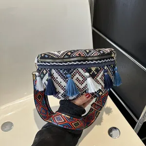 Détail macro du sac de poitrine bohème tissé avec motifs géométriques colorés et longs pompons