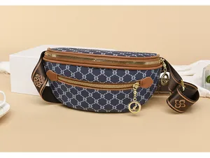 Dettaglio del marsupio blu con monogramma e finiture in pelle marrone e cerniere dorate