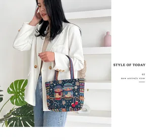 Detail of embroidered owl patterns and colorful bohemian straps on a blue canvas tote bag