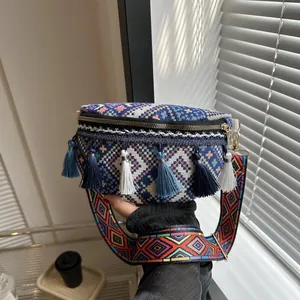 Détail d'un sac bohème tissé avec motifs géométriques colorés et décoration de glands bleus