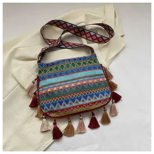 Detail of bohemian woven bag featuring colorful tassels and geometric patterned strap