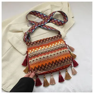 Close-up of bohemian knitted crossbody bag with colorful fringe and woven strap