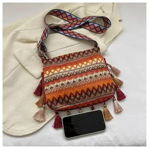 Detail of bohemian crossbody bag with colorful tassels and wide patterned shoulder strap