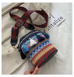 Dettaglio della borsa a secchiello boho con ricami vivaci, nappe blu e tracolla ricamata