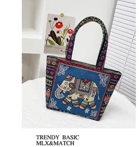 Detail of blue ethnic tote bag with golden elephant embroidery and colorful woven handles