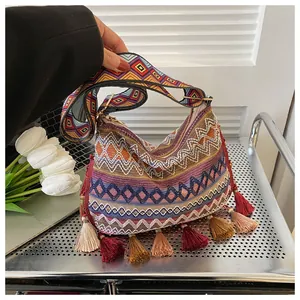 Detail of bohemian woven crossbody bag with colorful tassels and wide patterned strap