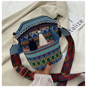 Dettaglio borsa a secchiello boho con motivi jacquard colorati e nappe di seta blu