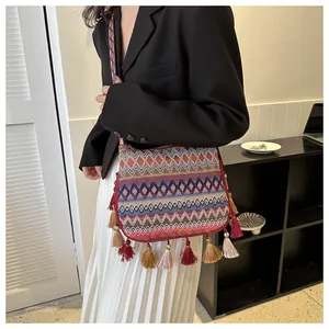 Detail of bohemian woven crossbody bag with geometric patterns and colorful fringe tassels